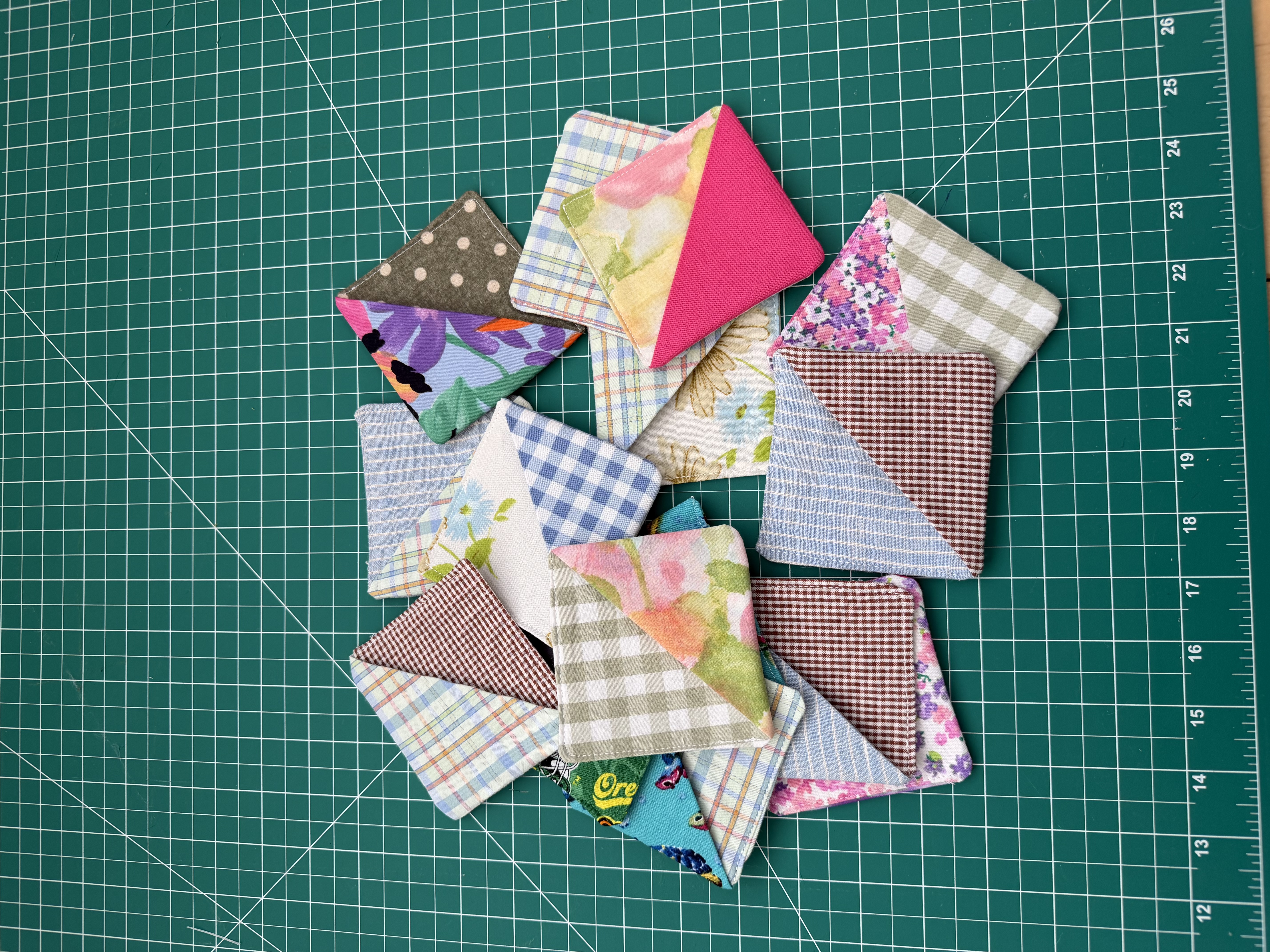 A fan of fabric corner bookmarks next to a book with two of them clipped onto the page corners